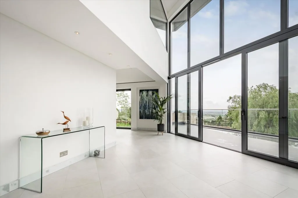 Double-height interior with a large multi-pane glazed wall and a glazed balcony front