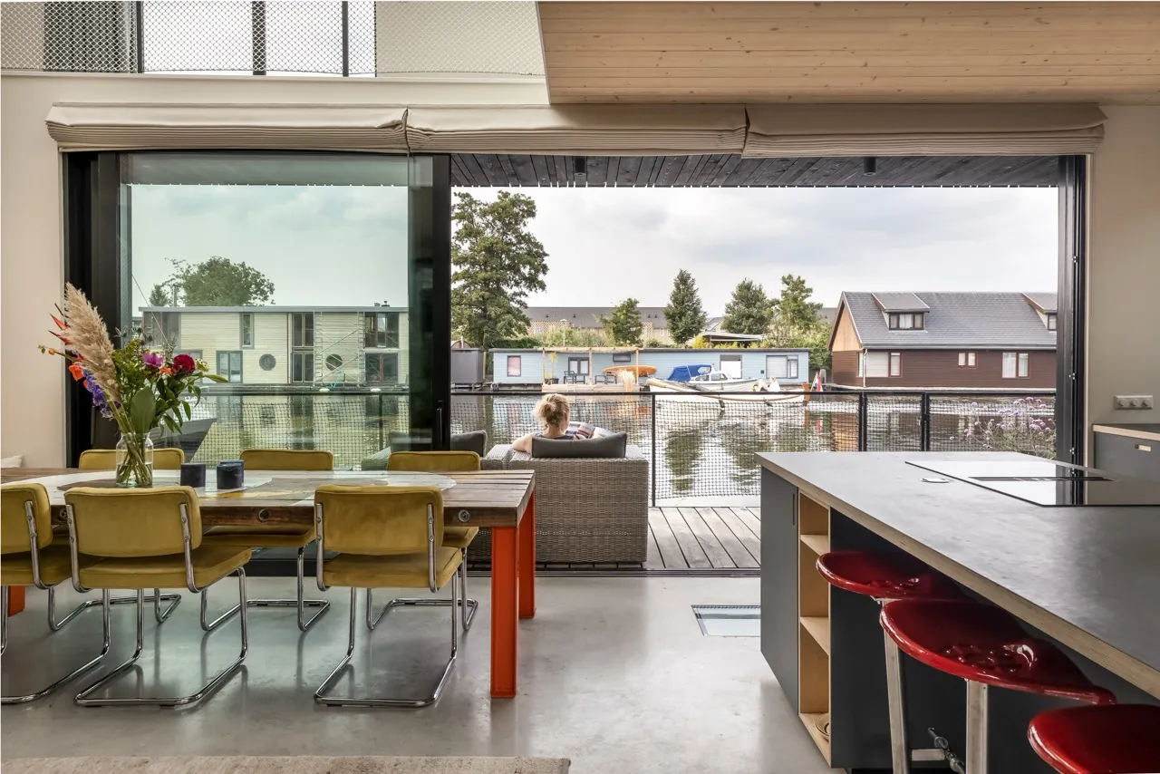 Kitchen and dining space behind a full-height glazed wall with sliding leaves onto the waterside