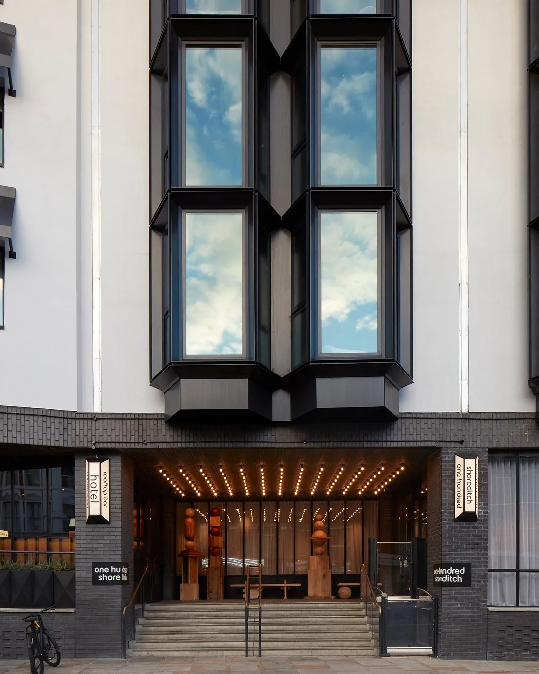 Frontal view of a building elevation with rows of black-framed projecting bay window units
