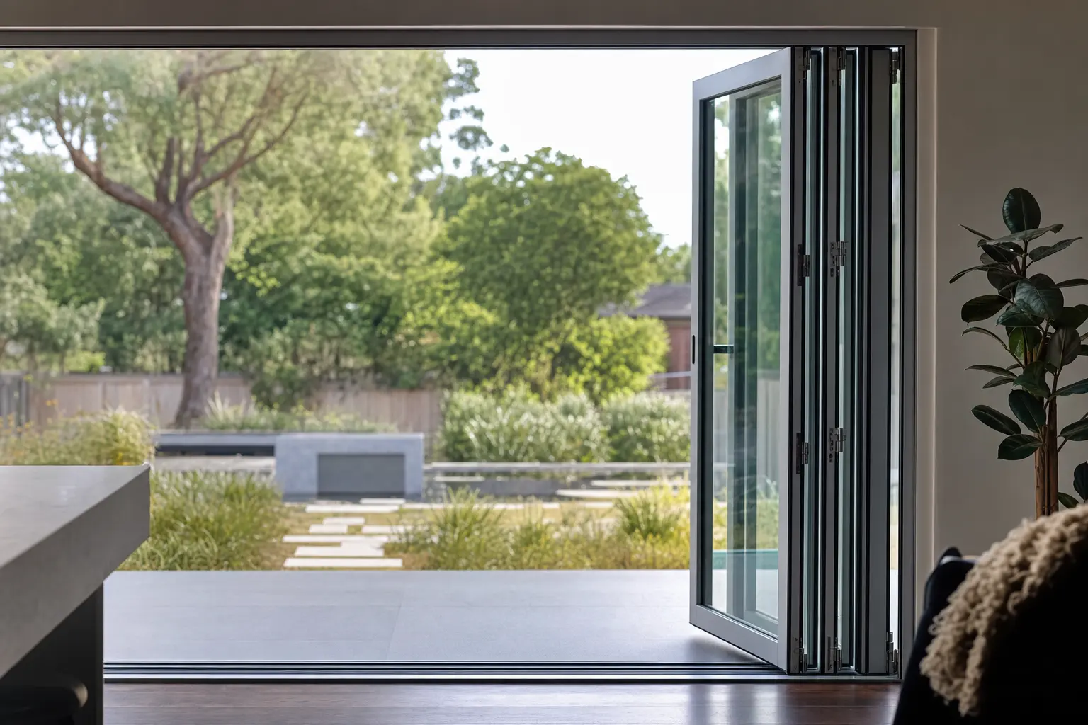 Interior view of a folding door stacked to one side, opening a living space onto a garden