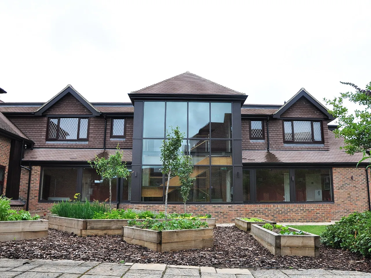 Glazed gable box projecting from a brick and tile house, framed in dark aluminium
