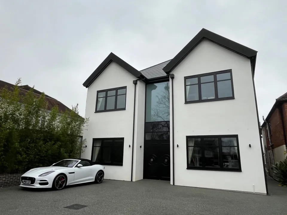 White rendered house with black-framed windows in several sizes across two storeys