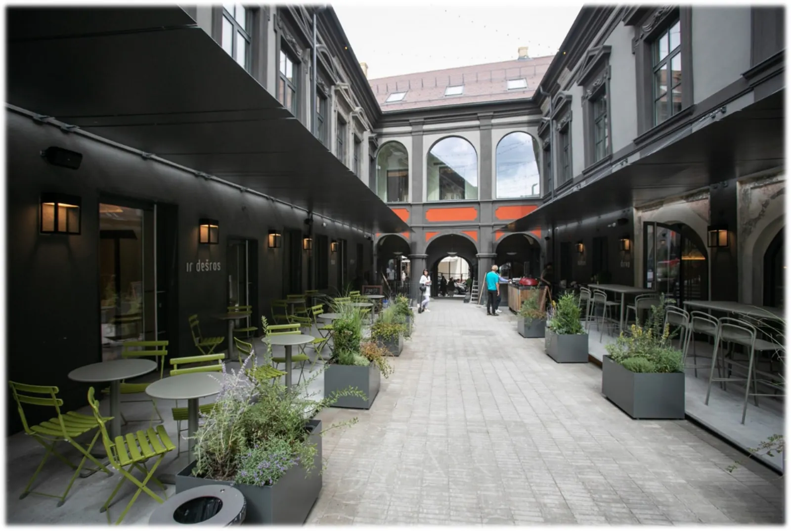 Covered walkway with a dark glazed frontage of tall window and door units