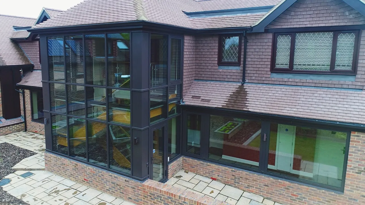 Detail of a glazed gable box showing the corner junction between glass panes and the surrounding brickwork