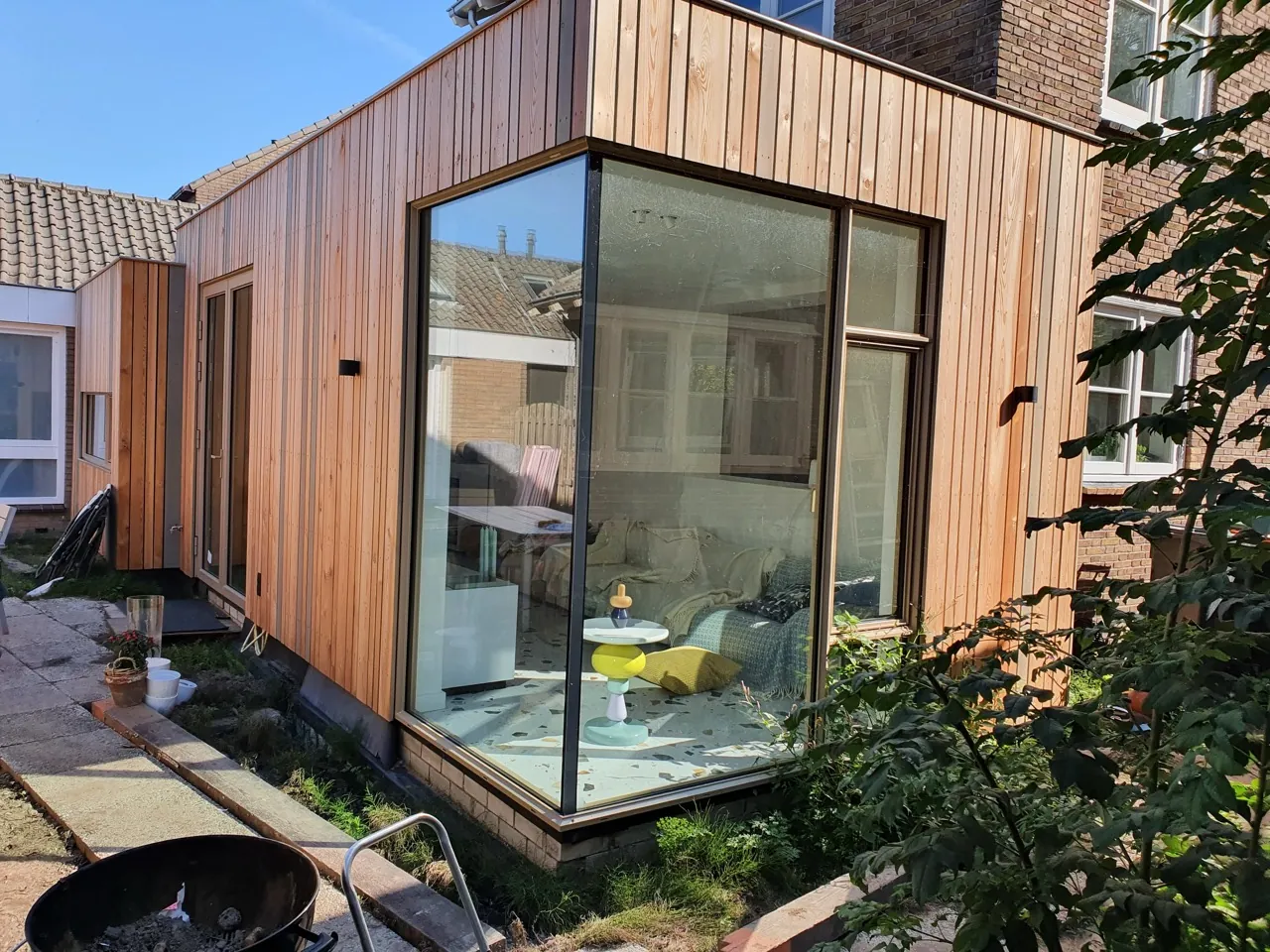 Timber-clad extension with a corner glazed unit and adjoining sliding door set